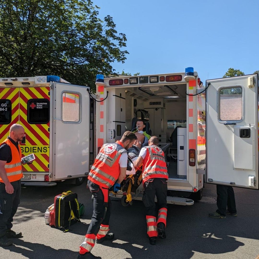 Blick zwischen zwei Rettungswachen hindurch auf die Mitarbeitenden in der neuen Fahrzeughalle